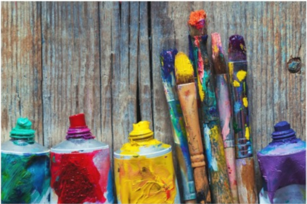 Tubes of acrylic paints green, red, yellow, blue and dirty paint brushes covered in paint.