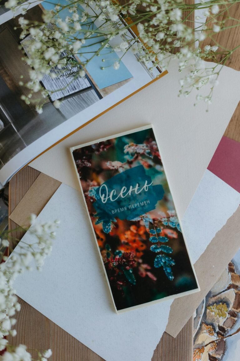 A creative flat lay featuring an autumn-themed journal surrounded by soft textures and delicate flowers.